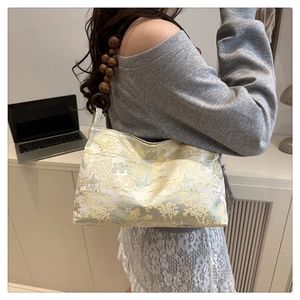 Close-up of silk underarm bag with gold oriental embroidery and wooden bead strap