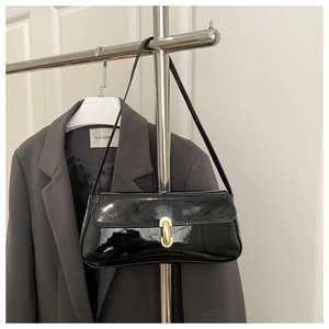 Detail of black patent leather baguette bag with a gold twist lock and a sleek finish