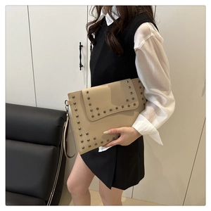 Beige envelope clutch bag with silver square studs styled with professional outfit
