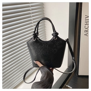 Close-up of black bucket bag featuring cartoon embossing and a unique knotted handle