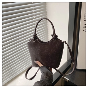 Detailed view of dark brown bucket bag featuring embossed heart and rabbit patterns