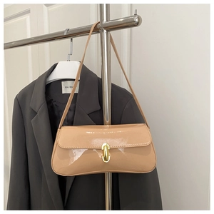 Detail of beige patent leather baguette bag with gold buckle on a stylish suit background