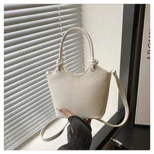 Detail of white bucket bag with embossed rabbit and heart patterns and knotted handle