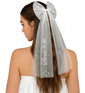 Detail of white bridal bow hair clip with pearls and Bride to be embroidery veil