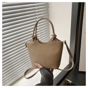 Detail view of khaki bucket bag with embossed cartoon patterns and knotted handle design