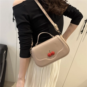 Minimalist beige crossbody bag with wavy flap design and red cherry charms detail