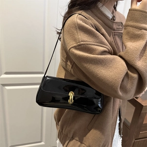 French baguette shoulder bag in black patent leather with golden U-shaped buckle on a model