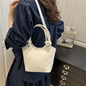 Fashionable white embossed bucket bag with top handles and adjustable shoulder strap