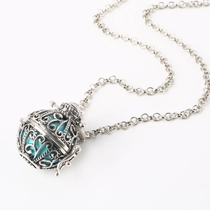 Detail view of hollow silver pendant necklace with an sky blue orb on white background