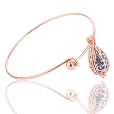 Detalle macro de pulsera oro rosa con jaula de lágrima y colgante de cuenta azul
