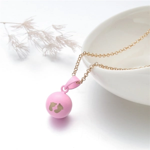 Detailed shot of pink baby feet harmony ball pendant on a delicate gold chain