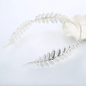 Detailed top view of silver leaf crown headband with intricate metallic texture on white plate