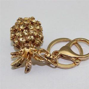 Detail of a golden pineapple keychain featuring yellow crystals and a metal lobster clasp