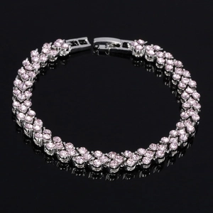 Détail d'un bracelet trèfle argenté avec cristaux roses sur surface noire miroir