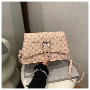 Detail of pink crossbody bag with M-pattern texture and silver metal chain strap