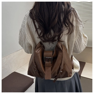 Detailed view of dark brown retro leather backpack with metal buckle and pleated design