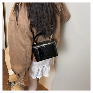 Detail of black patent leather vanity case with gold hardware and removable shoulder strap