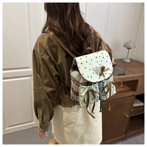 Detail of mint green and brown plaid mini backpack with black star and bow accents