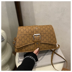 Detail of printed leather crossbody bag with silver metal chain and M pattern