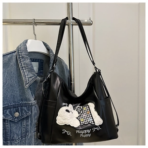 Detail of soft matte black tote bag with white plush puppy patch and Happy Puppy text