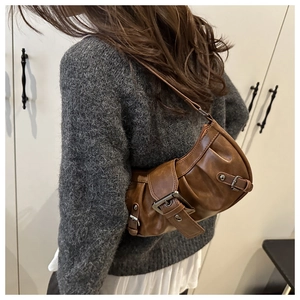Retro brown crescent shoulder bag featuring pleated texture and metal buckle detail on model