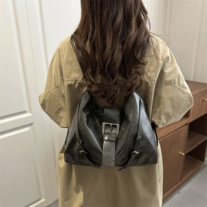 Versatile black PU leather backpack with buckle straps shown on model in khaki trench coat