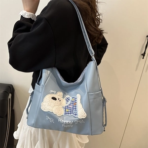 Blue tote bag with Happy Puppy embroidery and white bow shown on a female model