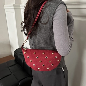 Red suede crescent underarm bag with gold rivets and metallic eyelet details