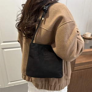 Sac seau classique en daim noir avec embossage porté à l'épaule par un mannequin