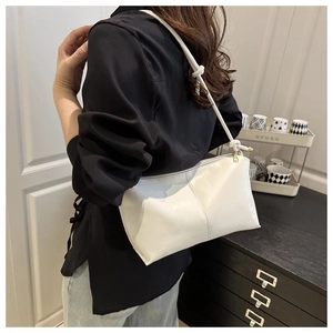 Detail of white leather shoulder bag with gold zipper and knotted strap design