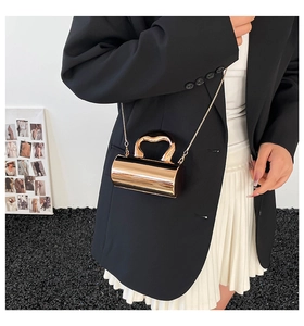 Detail of rose gold cylindrical evening bag with heart-shaped handle and metal chain strap