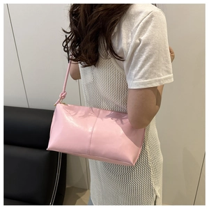 Detail of pink PU leather underarm bag with knotted shoulder strap worn by a model
