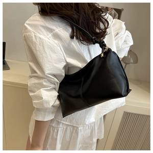 Detail of black leather underarm bag with unique knotted strap and gold hardware