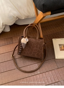Macro detail of retro leopard print crossbody bag with plush charm and leather strap