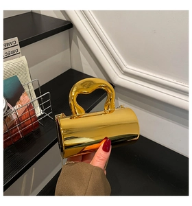 Close-up of golden cylindrical evening bag with unique organic handle and chain