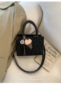 Detail of leopard print crossbody bag with cute charm and textured material