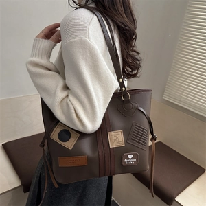 Brown vintage faux leather tote bag with stylish patches shown on a shoulder