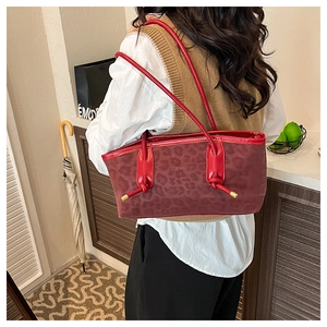 Detail of red leopard print tote bag with stylish knot strap and textured suede finish