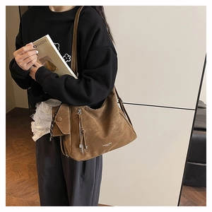 Détail du sac hobo marron vintage avec fermeture à franges et pochette assortie