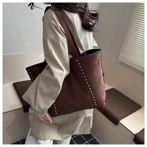 Détail du grand sac cabas en daim marron avec des rivets argentés vintage sur les côtés