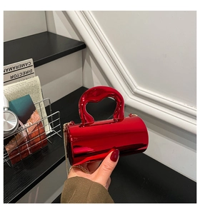 Close-up of metallic red cylinder evening bag with sculptural handle and gold chain