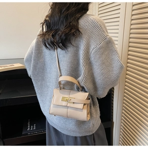 Mini beige leather Kelly bag with gold buckle shown on model in knit sweater