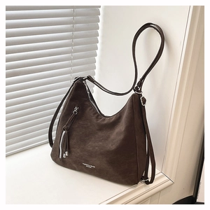 Détail d'un sac hobo en cuir mat marron foncé avec de longues fermetures éclair à franges