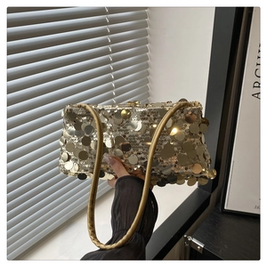 Détail d'un sac à bandoulière en paillettes dorées avec anse en cuir sous le soleil