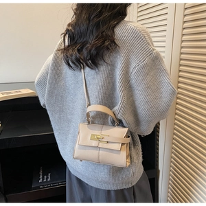 Side view of beige leather Kelly style mini bag with silver clasp lock on a model