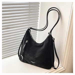 Détail du sac hobo noir en daim avec fermetures éclair argentées et lettrage de mode