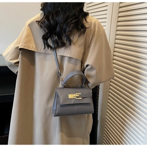 Detail of grey crossbody bag showing faux leather grain and golden rotary lock