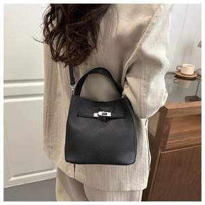 Detailed view of black pebbled leather bucket bag with metallic twist lock and top handle
