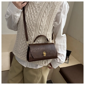 Close-up of vintage brown crossbody bag featuring golden twist lock and faux leather texture