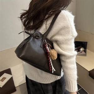 Retro dark brown tote bag with side bow detail and stylish charm pendant shown on shoulder